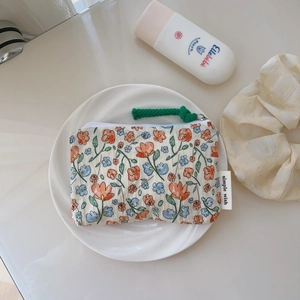 Mini porte-monnaie en coton à fleurs avec fermeture éclair sur une assiette blanche