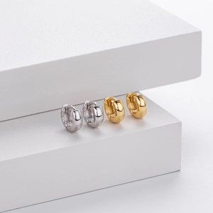 Detailed macro view of S925 sterling silver and gold hoop earrings on minimalist display