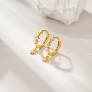Detail of gold-plated silver hoop earrings featuring star pendants and clear cubic zirconia