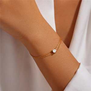Detail of a minimalist gold-plated silver double-layer bracelet with a round zircon on wrist