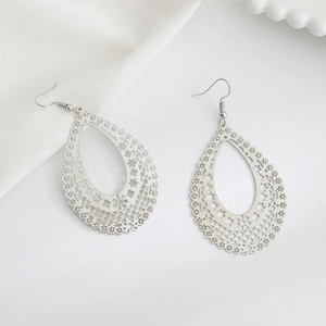 Silver teardrop hollow floral drop earrings in bohemian style on white silk background