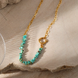 Detail of bohemian gold chain necklace with irregular turquoise stones on stone background