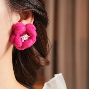Gros plan de boucles d'oreilles fleurs en feutre rose avec perles sur un mannequin