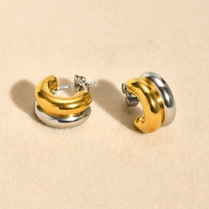 Macro detail of intertwined gold and silver double-layered C-shaped hoop earrings