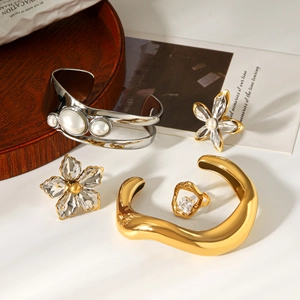 Flat lay of gold and silver jewelry with crystal flower charms and pearl bracelet