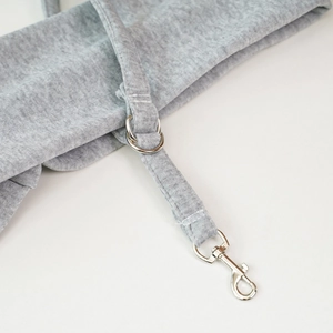 Primer plano del detalle de la correa de la bolsa para mascotas gris con anillos de metal.