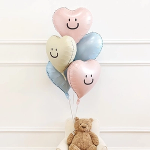 Smiley heart-shaped foil balloons in pastel colors with a cute brown teddy bear decoration