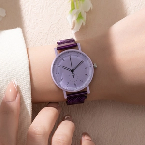 Gros plan d'une montre à quartz violette avec bracelet en maille portée au poignet