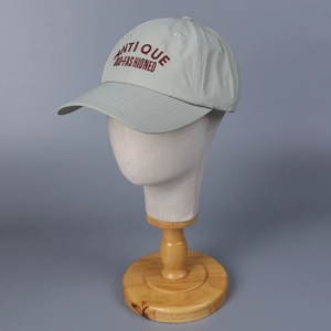 Detail view of burgundy antique embroidery on a light gray nylon quick-dry baseball cap