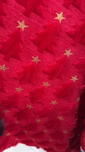 Close-up of red plush fabric with golden star patterns on the heart-shaped pillowcase