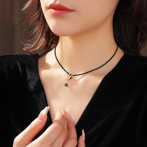 Macro view of a gold pendant with black crystal beads on a black velvet dress