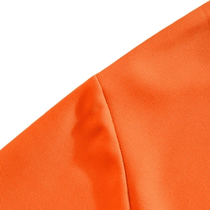 Detailed close-up of orange breathable piqué mesh fabric on a short-sleeved polo shirt