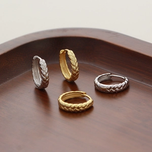 Close-up of S925 silver wheat-ear hoop earrings in gold and silver on a wooden tray