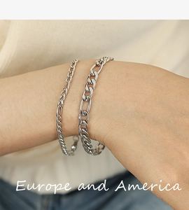 Detail of layered silver Figaro chain bracelets worn by model with metallic luster