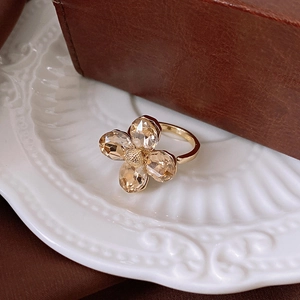 Macro shot of gold floral ring featuring four champagne faceted crystal flower petals