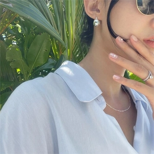 Outdoor model shot showing silver teardrop earrings with matching ring and necklace