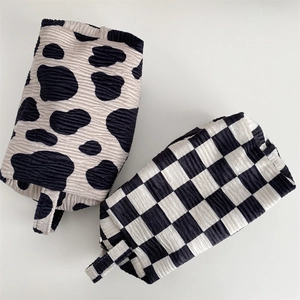 Detail of bubble textured velvet cosmetic bags in cow print and checkerboard patterns