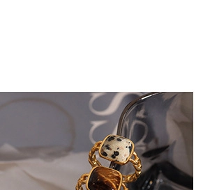 Macro shot of gold braided chain rings with square white and brown natural stones