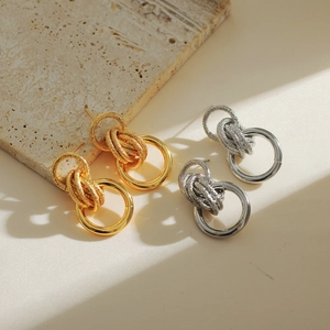 Modern 18K gold and silver multi-layer geometric hoop earrings on a stone background