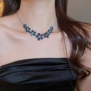 Detailed close-up of a zircon flower cluster necklace set in navy blue and gold on a model