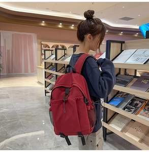 Detailansicht des dunkelroten Rucksacks mit Kordelzug und Netztaschen in einer Bibliothek