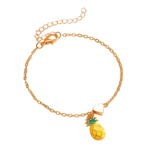 Dettaglio di un braccialetto dorato con ciondoli a forma di cuore e ananas