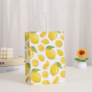 Detail view of lemon print paper bag with white twisted rope handles on a bright desktop