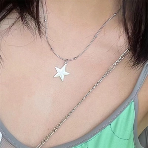 Close-up of minimalist star pendant necklace with silver chain worn on the neck