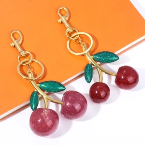 Detailed view of resin cherry keychains with green leaves and gold lobster clasps