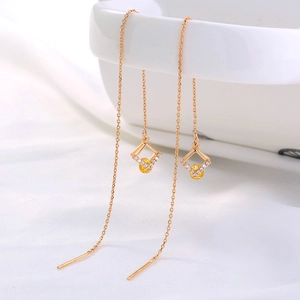 Close-up of elegant gold tassel earrings with yellow crystal rhombic geometric pendant