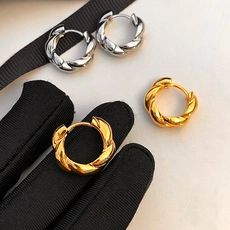 Macro shot of minimalist twisted gold and silver hoop earrings with a metallic finish