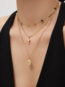 Close-up of golden layered necklaces with cross pendant and Virgin Mary medallion charm