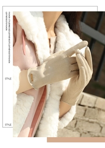 Close-up of beige suede winter gloves with elegant gold metal fashion tag detail