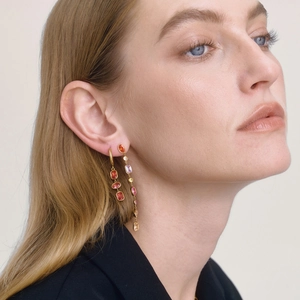 Goldene Ohrringe mit bunten Zirkon-Quasten, getragen von einem Modell in Mode-Stil