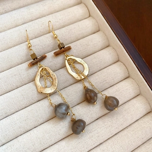 Ethnic style wood and metal tassel earrings with gold hooks and grey beads in a jewelry box