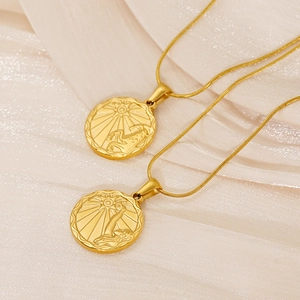 Dettaglio ravvicinato di ciondoli zodiacali dorati con rilievo del Capricorno e motivi celesti