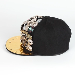 Dettaglio cappellino con borchie metalliche, punte e stemma con testa di leopardo dorata