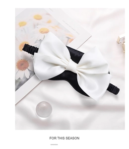Elegant silk sleep mask with a large white bow on a soft pink satin background detail