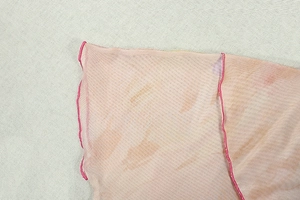 Gros plan du tissu en maille dégradé rose-orange avec bordure ondulée et texture