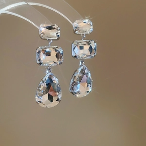 Macro detail of tiered cascading teardrop earrings with square crystals and silver chain