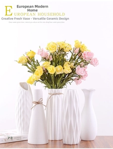 Detailed view of white ceramic vases with geometric textures and artificial roses