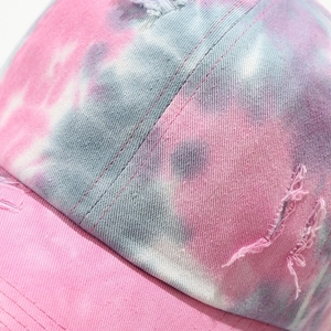 Close-up of distressed tie-dye baseball cap with pink and blue cotton canvas texture