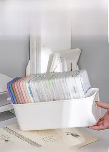 White plastic storage box with handles containing various phone cases for desk organization