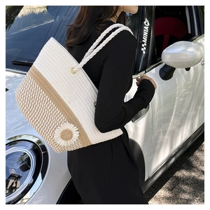 Outdoor shot of a woven flower tote bag worn by a model leaning against a car