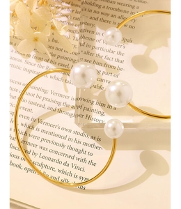Macro view of gold plated hoop earrings with elegant pearls on vintage book background