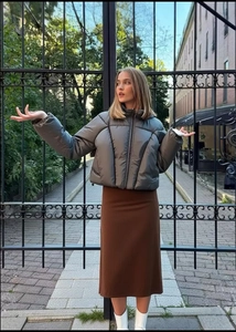 Short metallic grey puffer jacket paired with skirt in an urban street setting