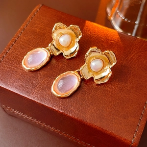Detail of vintage flower earrings with pearl and pink stone on a brown leather case
