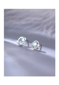 Macro shot of silver Saturn earring with blue cat-eye stone and crystal accents