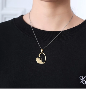 Close-up of a gold stainless steel necklace with a hollow cat pendant worn by a model