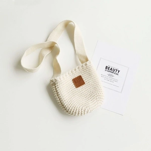 Vista piatta di borsa a tracolla in maglia bianco panna per bambini con toppa in pelle